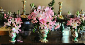 Flowers arranged in three green vases.